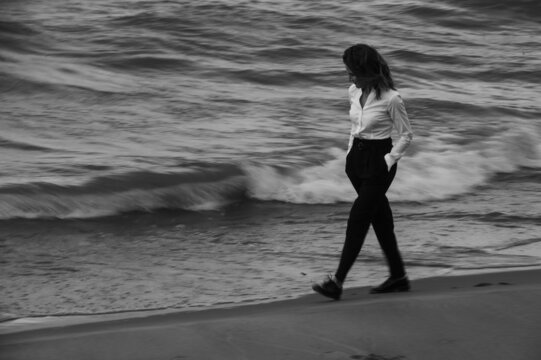 moody portrait of a woman walking by the sea