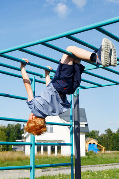 Unrecognizable boy hanging on monkey bars