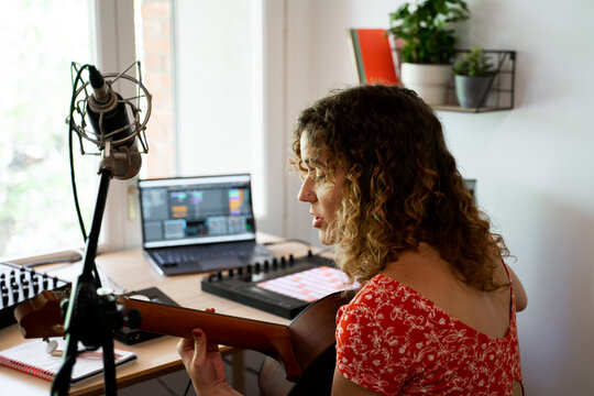Woman playing and recording music at home studio