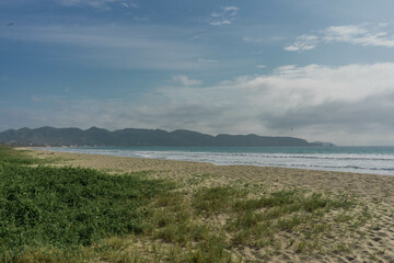 Clouds over the Beach with green grass growing on the sand
