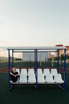 Lonely young man sitting on sports ground