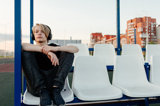 Adolescent in headphones sitting on grandstand