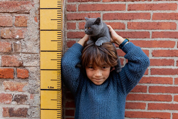 kid and cat against by measure tape