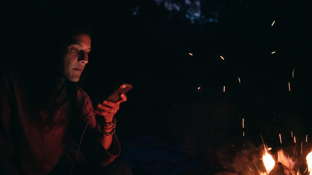 Beautiful girl on her phone by bonfire