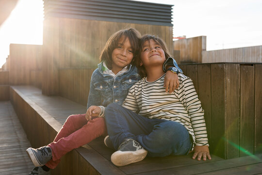 Brothers sitting on wooden deck at rooftop