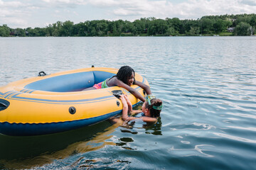 Black and caucasian girls in a lake with a boat
