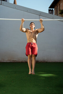 An athlete does pull-ups in an outdoor gym