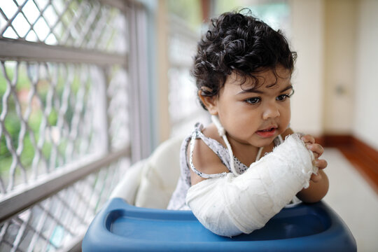 Toddler with broken arm in plaster case in her 
walker 