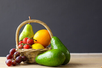 Assorted exotic fresh fruits in basket on wooden table