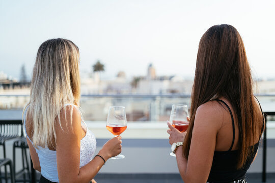 Unrecognizable girlfriends drinking wine on terrace