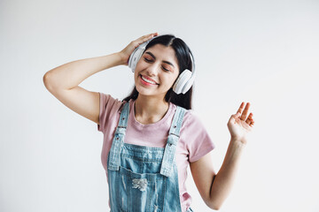 portrait of latin young smiling woman with headphones, dancing and listening music on a white background in Latin america
