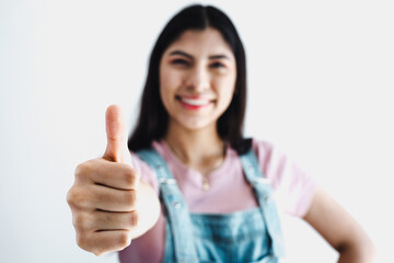 young latin woman smiling and showing thumbs up on a white background in Latin America