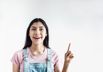 young latin woman pointing at copy space looks in camera in Latin America