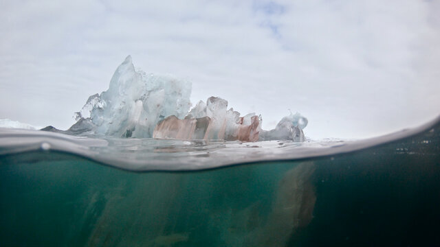 Melting translucent bergy bit of ice on water-line, Arctic Greenland