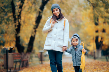 Happy Mom and Child Walking in the Park in Autumn Season