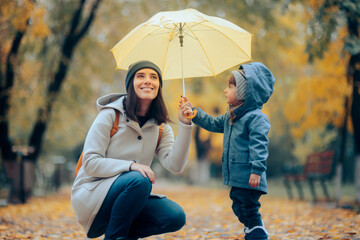 Little Girl Holding a Yellow Umbrella with her Mom in the park