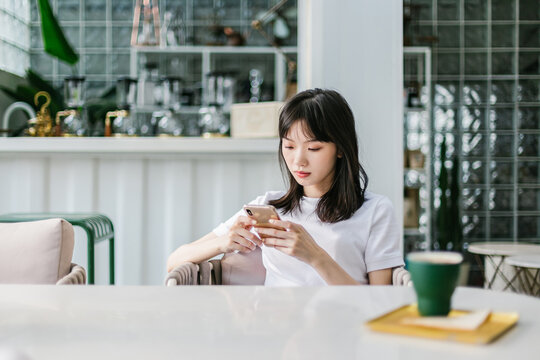Woman sitting in a cafe and playing mobile phone