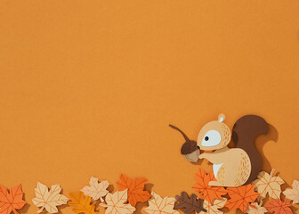 Paper squirrel  and autumn leaves on yellow background.
