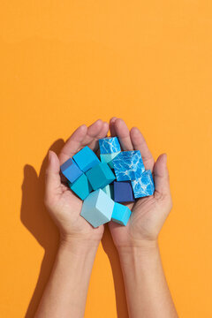 Elevated View Of A Human Hand Holding blue Cubes
