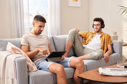 Men with gadgets on sofa.
