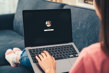 Woman sitting on sofa with typing the password on laptop computer, security and identification technology concept.