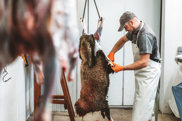 butcher removing skin from lamb