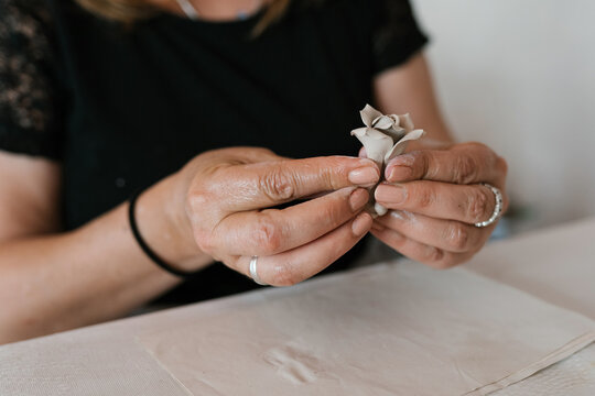 Crop female artisan shaping porcelain flower