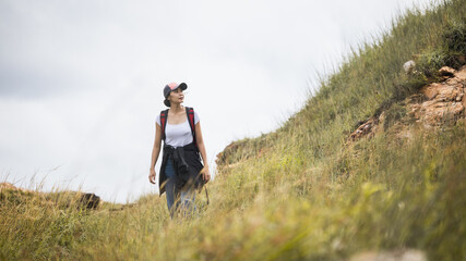 Naklejka na ściany i meble Woman traveler is walking on an outdoor adventure along the hillside. Travel and Lifestyle Concept