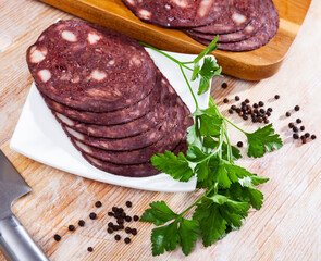 Thin slices of popular Catalan blood sausage (black botifarra) with herbs and spices on wooden...