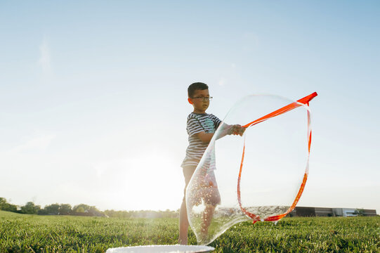 Boy playing with bubbles outdoors. 