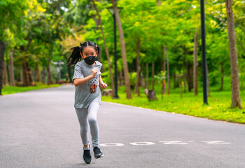 Asian child girl at 8 years old is running in the park, wearing protective medical mask, black long hair, front view, blank space for copy and design.