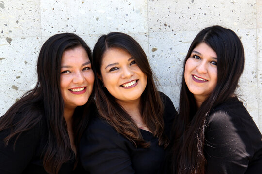 Happy black straight hair latin adult sisters dressed in black for family photo shoot in harmony and joy
