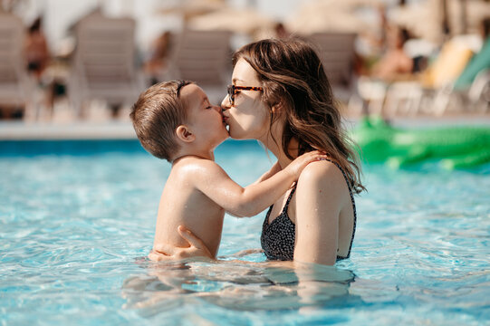 Mother kissing son in pool. - Powered by Adobe