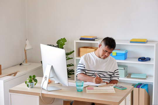 Businessman writing in notebook at workplace