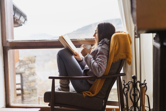Happy woman reading book and having coffe at home
