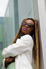 Empowered african american young woman wearing sunglasses looking at camera with a daring attitude. Vertical image.