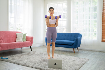 Young sporty woman in sportswear is sitting on the floor and watching online tutorials,Fitness...