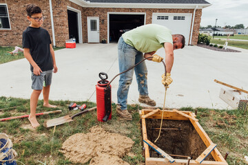 Worker spraying grease on wood frame. 