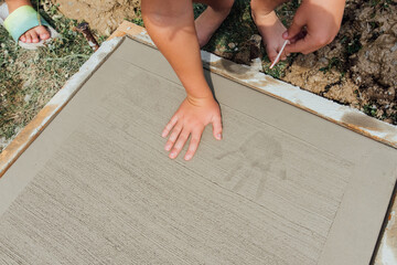 Person putting hand print in concrete. 