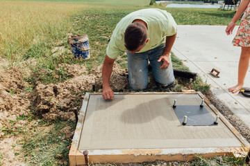 Person writing on fresh concrete. 