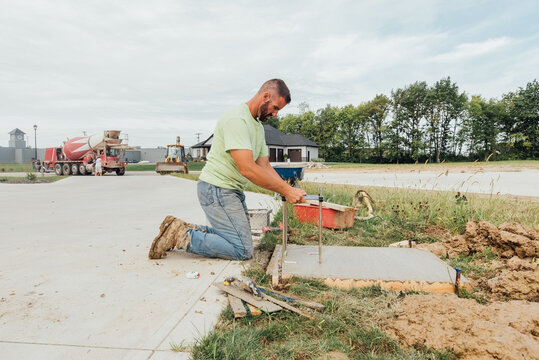 Worker placing form into concrete. 