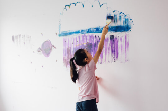 Little girl painting on the wall