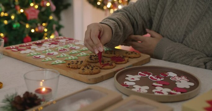 Asia happy adult people woman enjoy make craft gift for Xmas eve party snack cooking food recipe on kitchen table in good warm time. Cute smile gingerman bakery icing sugar with red green white color.