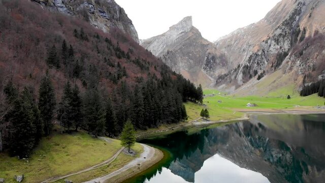 Aerial flyover from the shore of Seealpsee in Appenzell, Switzerland up above the lake revealing reflection of the Alpstein peaks