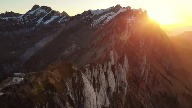 Aerial flyover over Schaefler in Appenzell, Switzerland at sunset from the mountain hut towards Altenalp Turm with the sun setting behind Santis