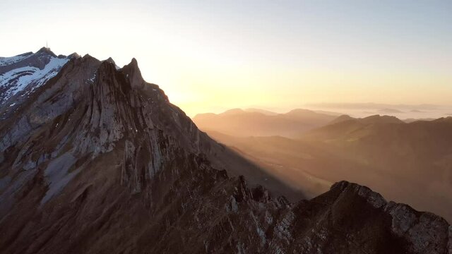 Aerial flyover over Schaefler in Appenzell, Switzerland with reverse motion revealing a person's silhouette against the sunset glow