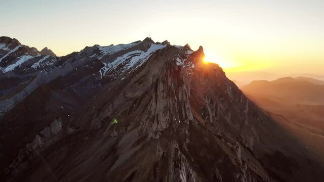 Aerial flyover over Schaefler in Appenzell, Switzerland at sunset as the sun disappears behind Santis