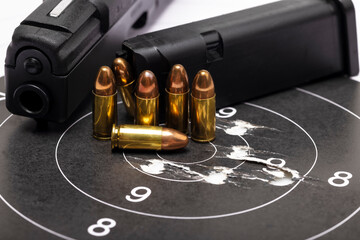 Gun bullets on bull eye paper target and semi automatic handgun background