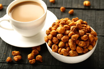 Bowl of spicy coated and roasted peanuts served with milk tea.