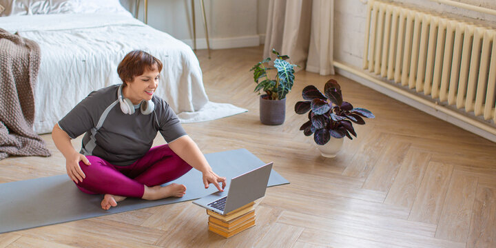 Senior woman preparing for a home workout under the guidance of an online instructor. Format photo 2x1.